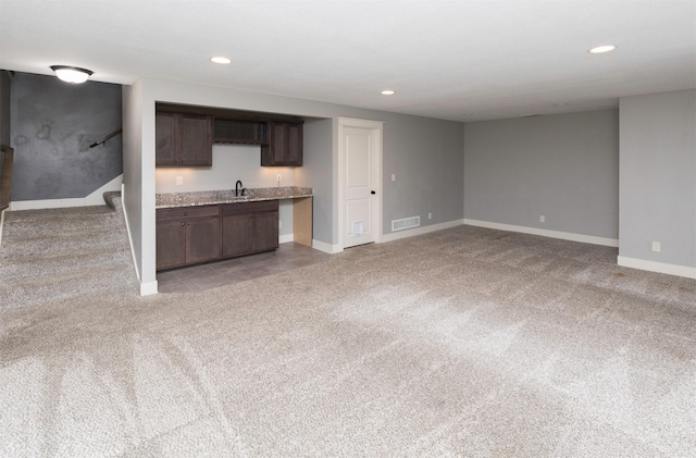 kitchen featuring dark brown cabinetry, light carpet, and sink