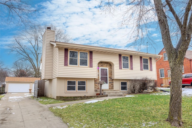 raised ranch featuring a garage, an outbuilding, and a front yard