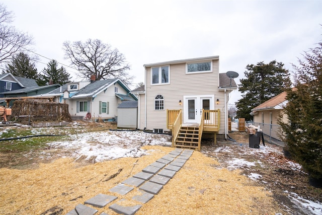 snow covered property with a wooden deck and french doors