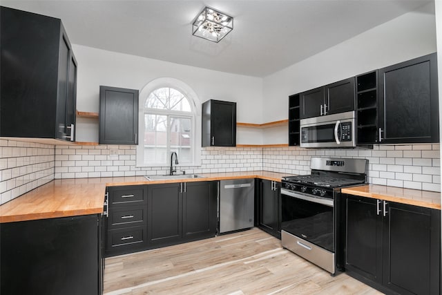 kitchen with decorative backsplash, stainless steel appliances, sink, light hardwood / wood-style flooring, and butcher block countertops