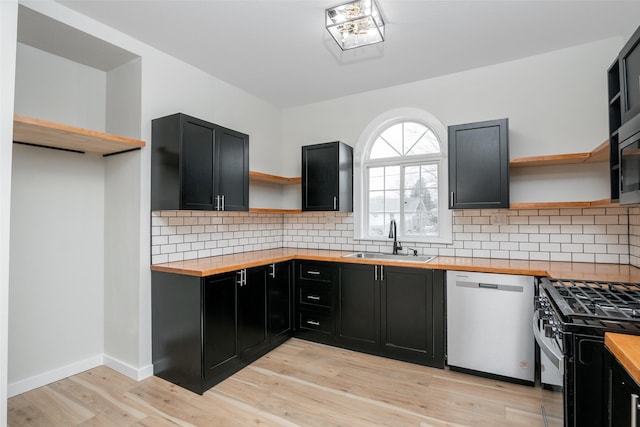 kitchen with sink, light wood-type flooring, appliances with stainless steel finishes, tasteful backsplash, and butcher block countertops