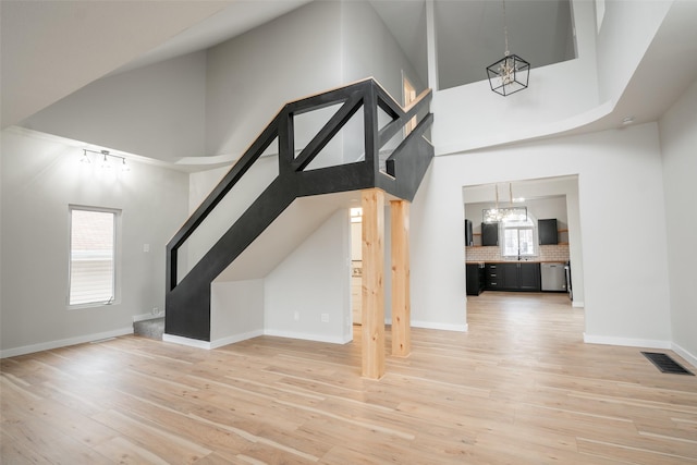 bonus room with sink, a towering ceiling, and light wood-type flooring