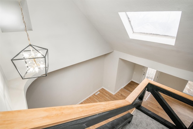 stairway with a skylight and hardwood / wood-style flooring