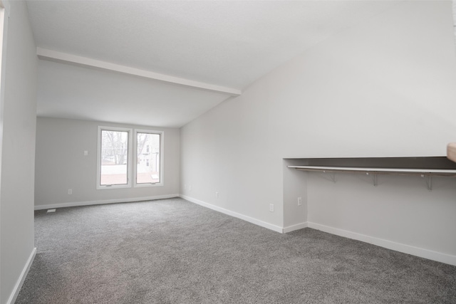 empty room with lofted ceiling with beams and carpet floors