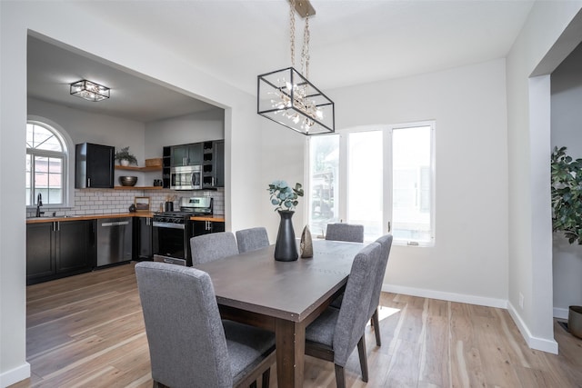 1141 Euclid Ave, Des Moines, IA 50313 - dining room featuring a chandelier, light wood-style floors, and baseboards