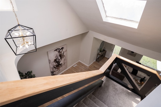 1141 Euclid Ave, Des Moines, IA 50313 - staircase with wood finished floors, a chandelier, vaulted ceiling, a skylight, and baseboards