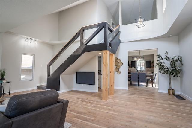 1141 Euclid Ave, Des Moines, IA 50313 - living area featuring a chandelier, stairs, light wood finished floors, healthy amount of natural light, and a towering ceiling