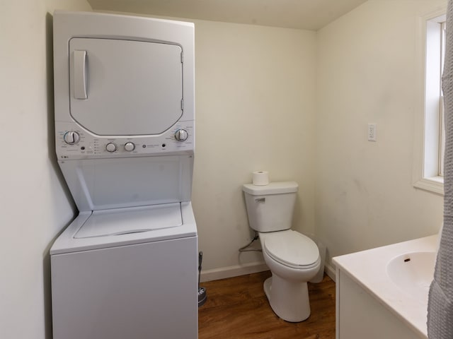 bathroom with vanity, toilet, wood-type flooring, and stacked washer and clothes dryer