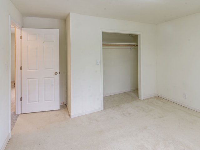 unfurnished bedroom featuring light carpet and a closet