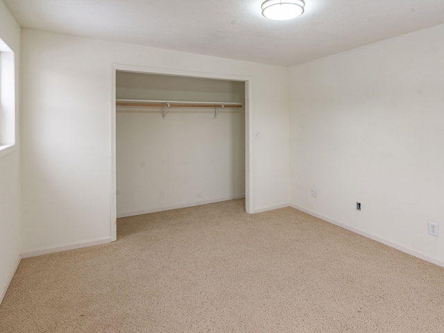 unfurnished bedroom featuring a closet and light colored carpet