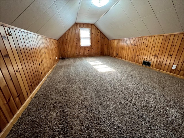 additional living space with carpet flooring, wooden walls, and lofted ceiling