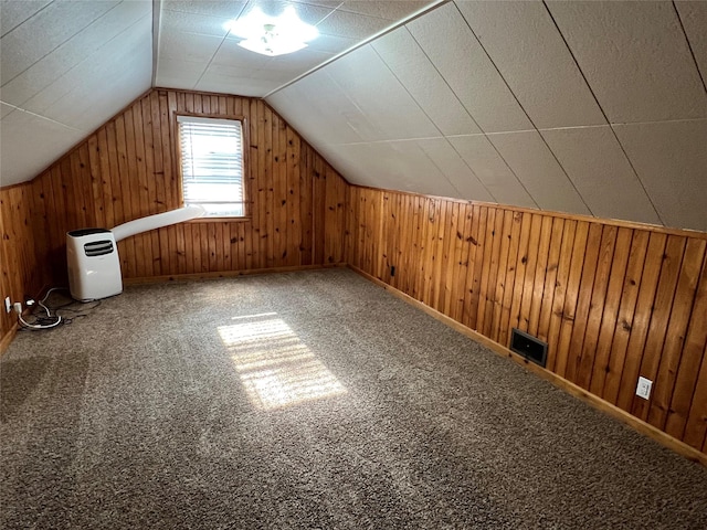 additional living space with wood walls, carpet floors, and vaulted ceiling