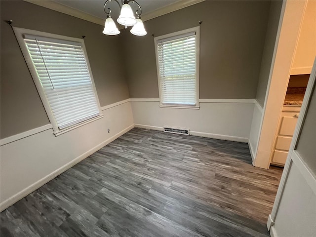 unfurnished dining area featuring dark hardwood / wood-style floors, ornamental molding, and a chandelier