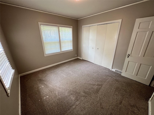 unfurnished bedroom with carpet, a closet, and ornamental molding