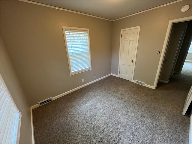 unfurnished bedroom with a closet, dark carpet, and ornamental molding