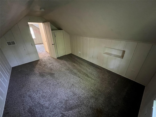 bonus room featuring dark colored carpet and lofted ceiling