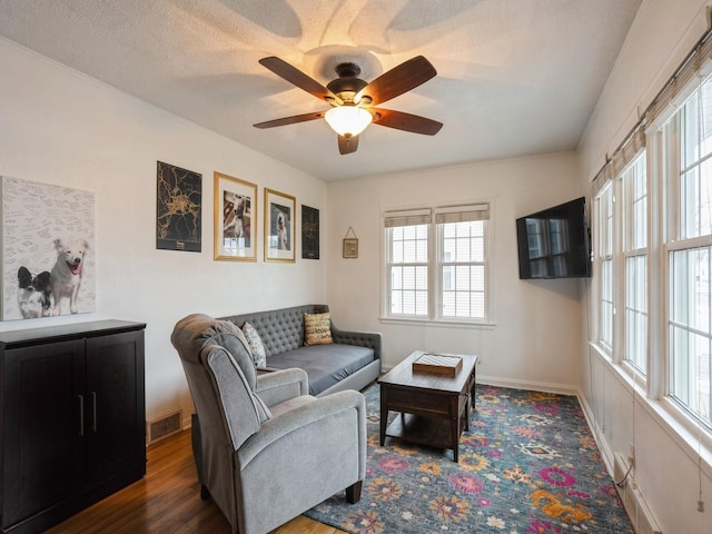 living room with ceiling fan, dark hardwood / wood-style flooring, and a textured ceiling