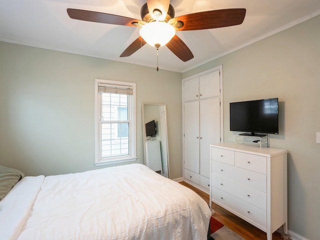 bedroom featuring a closet, dark hardwood / wood-style floors, ceiling fan, and crown molding