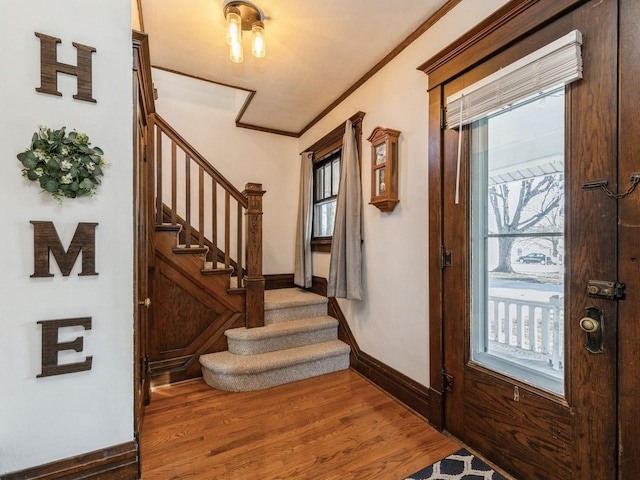 foyer entrance featuring a healthy amount of sunlight, ornamental molding, and hardwood / wood-style flooring