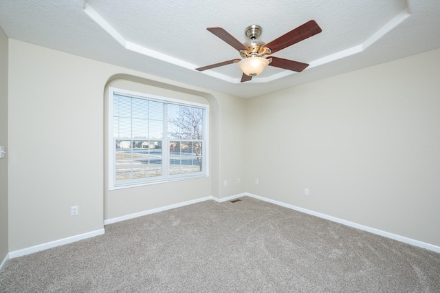 carpeted spare room featuring a tray ceiling, ceiling fan, and a textured ceiling