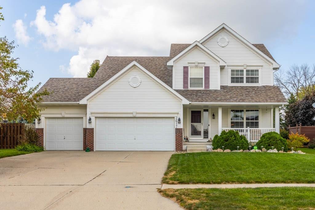 view of front of property with covered porch, a garage, and a front yard