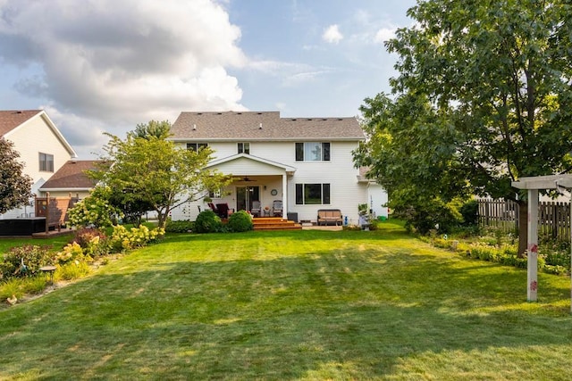 back of property featuring ceiling fan and a yard