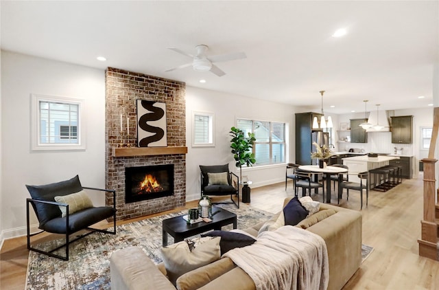 living room with ceiling fan, light hardwood / wood-style flooring, and a brick fireplace