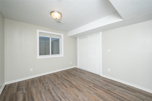 interior space with a textured ceiling, dark hardwood / wood-style floors, and a closet