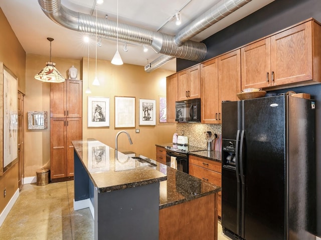 kitchen featuring dark stone counters, black appliances, sink, an island with sink, and decorative light fixtures