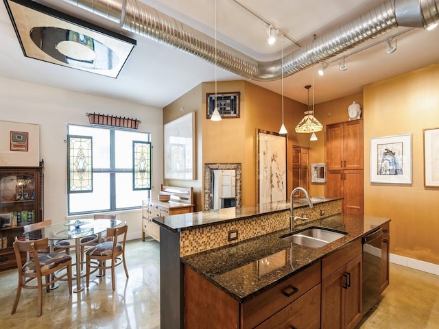 kitchen with pendant lighting, a kitchen island with sink, dark stone counters, sink, and dishwashing machine