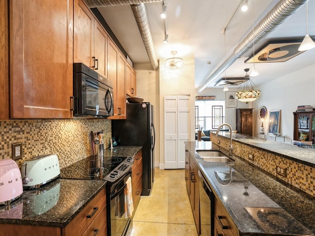 kitchen with dark stone counters, sink, black appliances, and decorative light fixtures