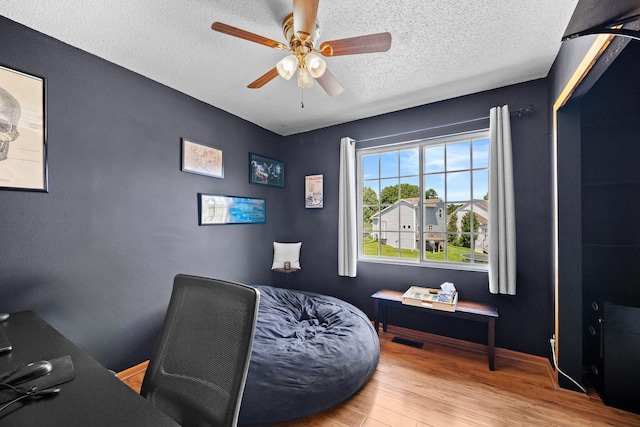 office space featuring ceiling fan, light hardwood / wood-style flooring, and a textured ceiling