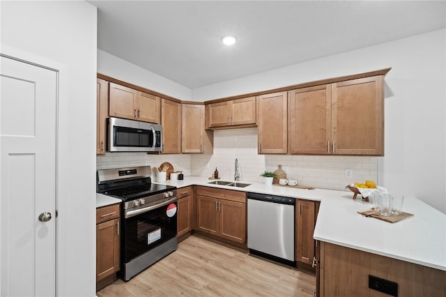 kitchen with tasteful backsplash, sink, light hardwood / wood-style flooring, and appliances with stainless steel finishes