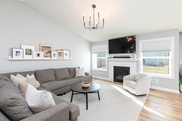 living room featuring hardwood / wood-style flooring, lofted ceiling, and an inviting chandelier