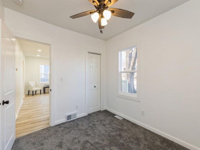 unfurnished bedroom with ceiling fan, a closet, carpet floors, and multiple windows