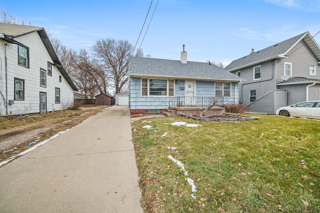 view of front facade with a garage, an outdoor structure, and a front yard