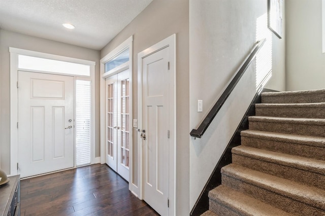 entrance foyer with dark hardwood / wood-style floors, a textured ceiling, and french doors