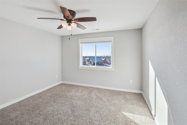 carpeted empty room featuring visible vents, ceiling fan, and baseboards