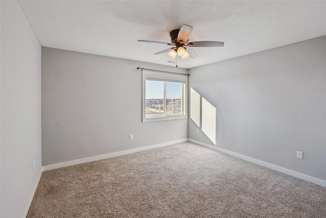 empty room featuring ceiling fan, carpet floors, a textured ceiling, and baseboards