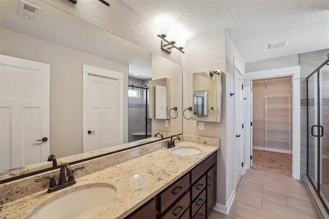 full bath with a stall shower, a walk in closet, a sink, and double vanity