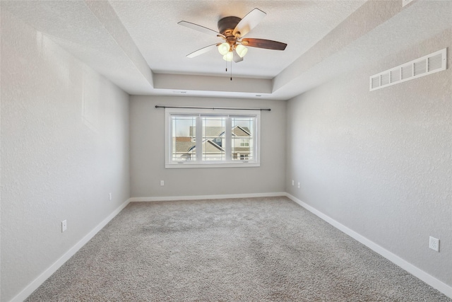 carpeted spare room with baseboards, visible vents, a raised ceiling, a textured wall, and a textured ceiling