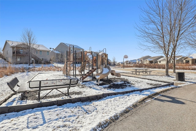 snowy yard with playground community and a residential view