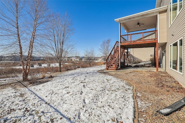 yard layered in snow with stairway, a wooden deck, and a ceiling fan