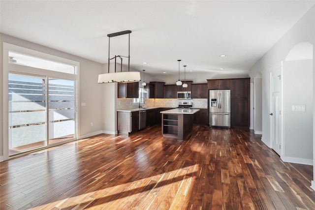 kitchen with a center island, hanging light fixtures, stainless steel appliances, light countertops, and a sink