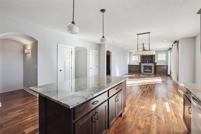 kitchen featuring open floor plan, light stone counters, and pendant lighting