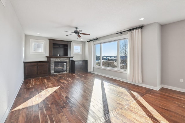 unfurnished living room featuring dark wood-style flooring, recessed lighting, a glass covered fireplace, ceiling fan, and baseboards