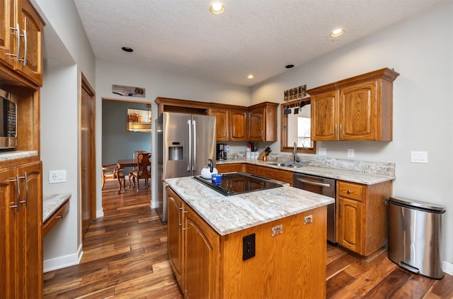 kitchen featuring light stone countertops, appliances with stainless steel finishes, sink, a center island, and dark hardwood / wood-style floors