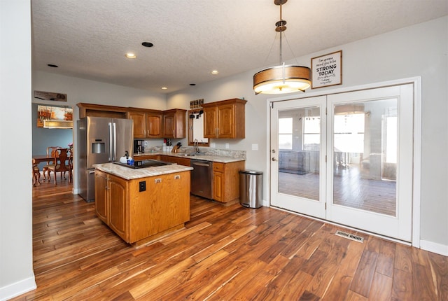 kitchen with sink, a center island, hanging light fixtures, dark hardwood / wood-style flooring, and appliances with stainless steel finishes