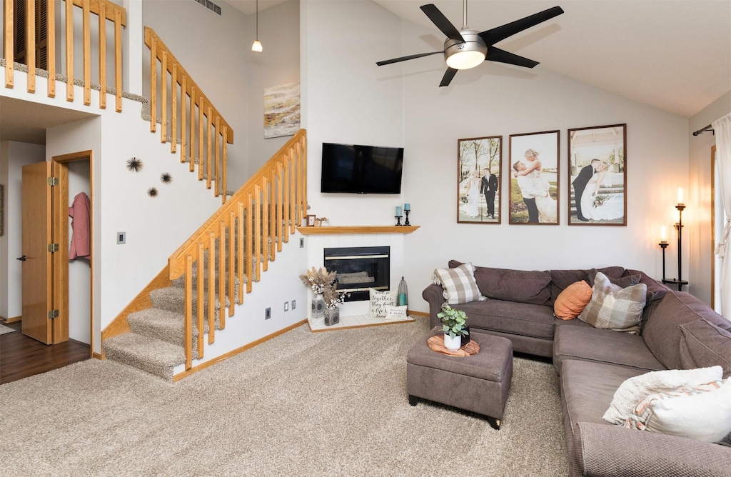 carpeted living room with ceiling fan and high vaulted ceiling