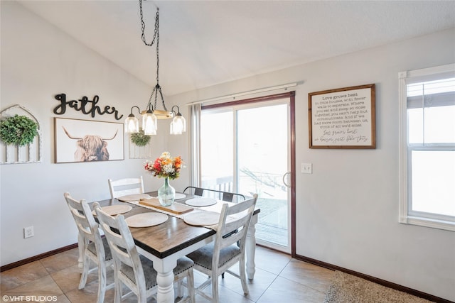 dining space with light tile patterned floors, a healthy amount of sunlight, vaulted ceiling, and an inviting chandelier